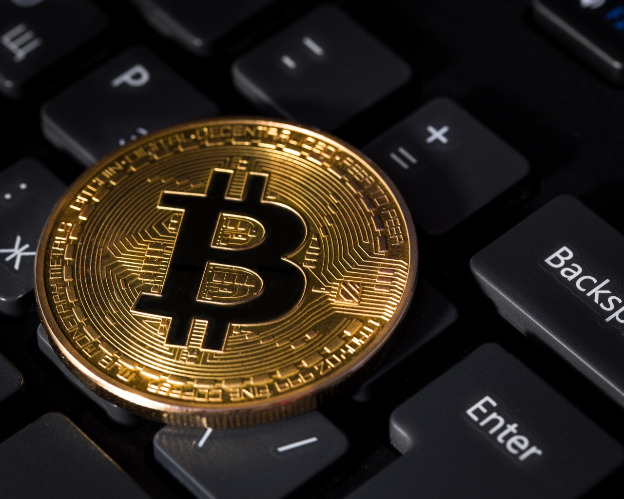 Coin bitcoin lies on a black keyboard