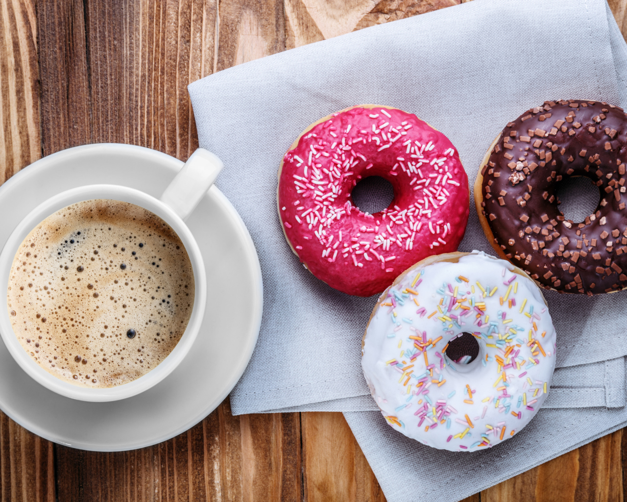 Чашка кофе с тремя аппетитными пончиками на столе