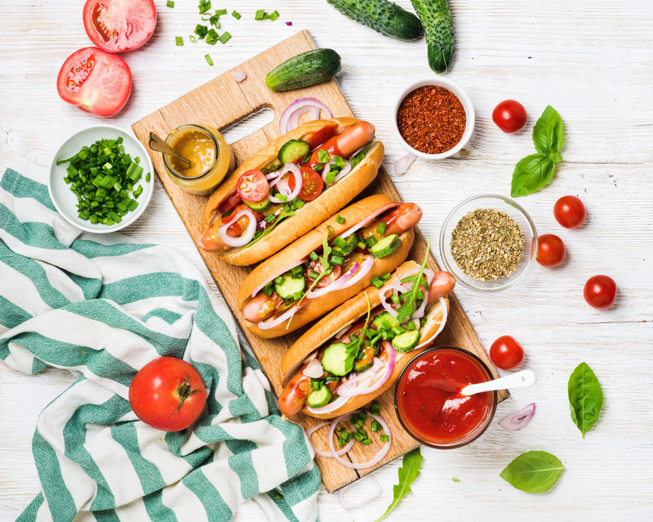 Аппетитные хотдоги на разделочной доске с овощами