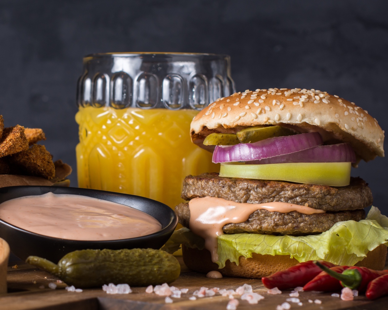 Аппетитный гамбургер на столе с соусом, овощами и соком