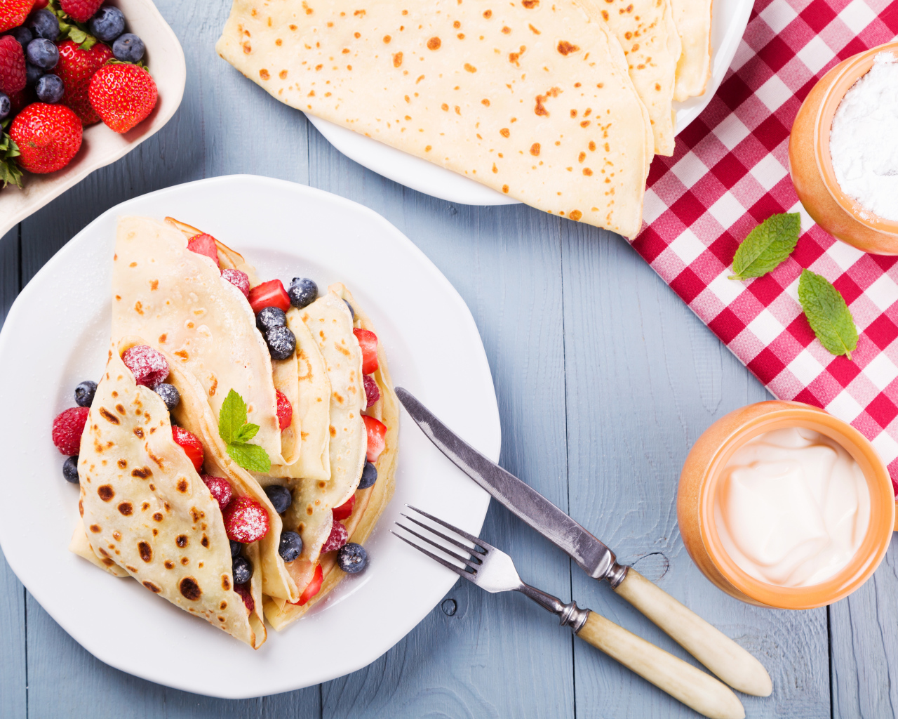 Аппетитные блинчики с ягодами на белой тарелке 