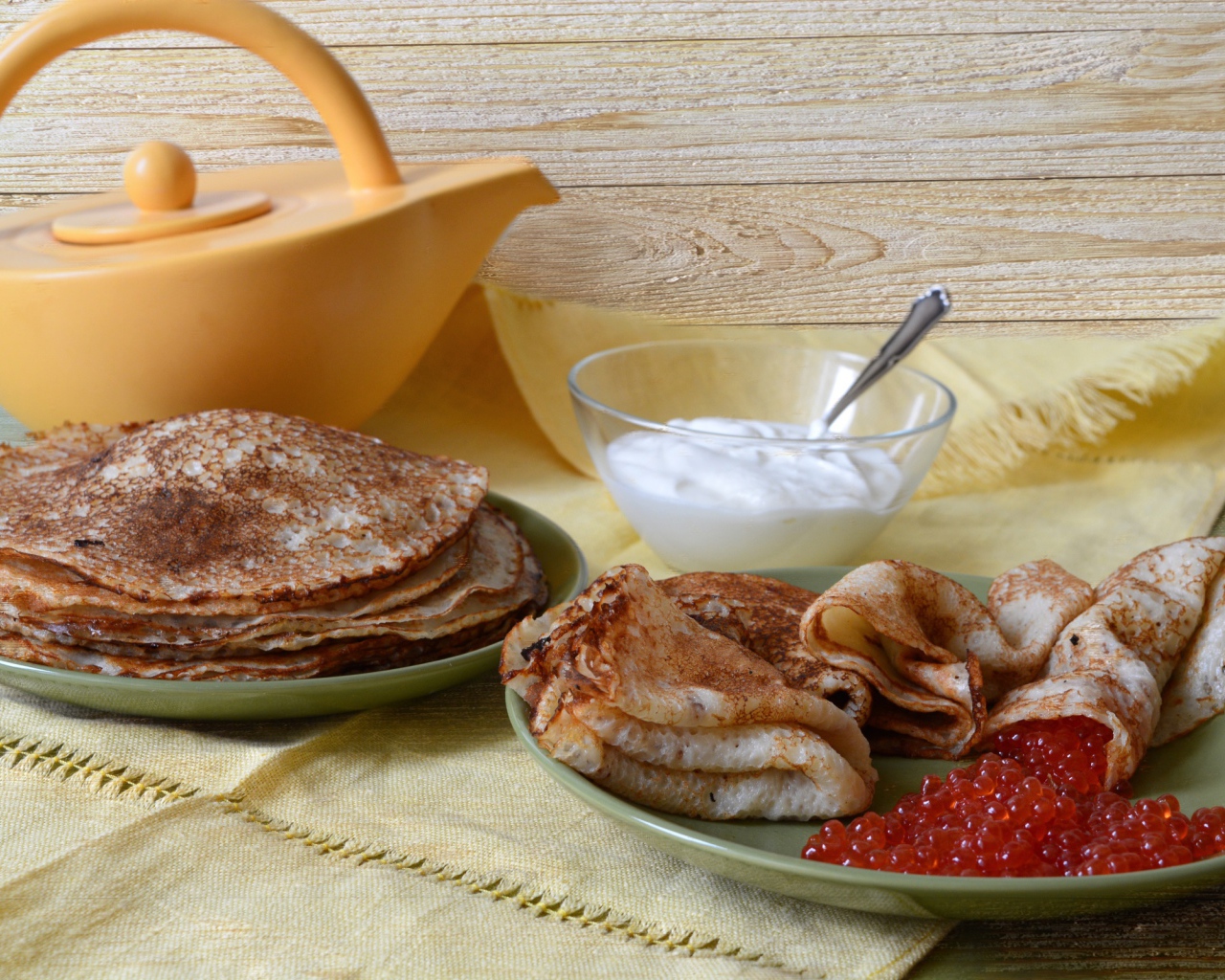 Аппетитные блинчики со сметаной и красной икрой на столе