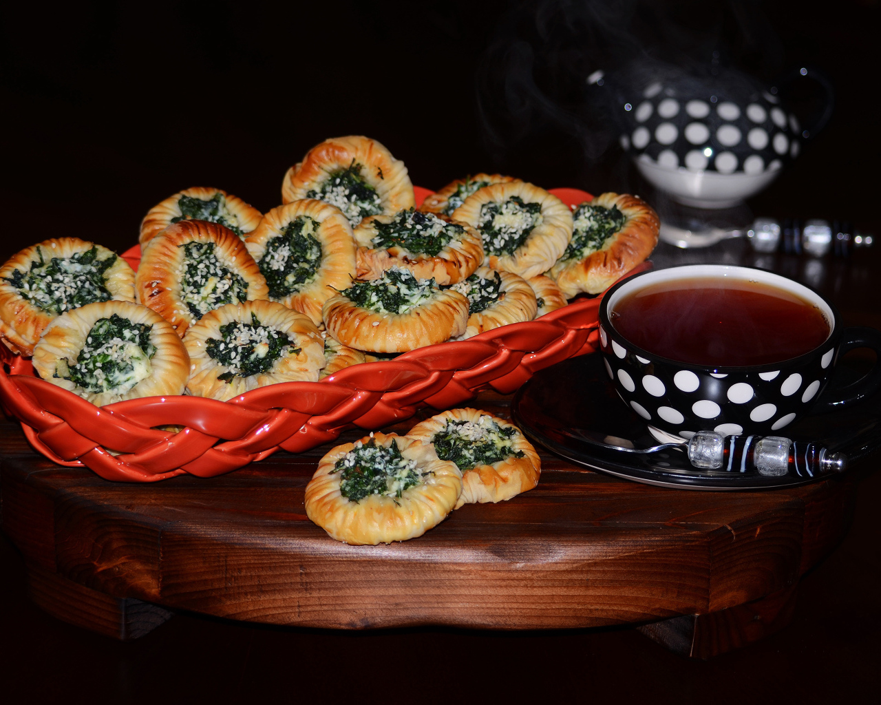 Булочки с зеленью и горячим чаем на черном фоне