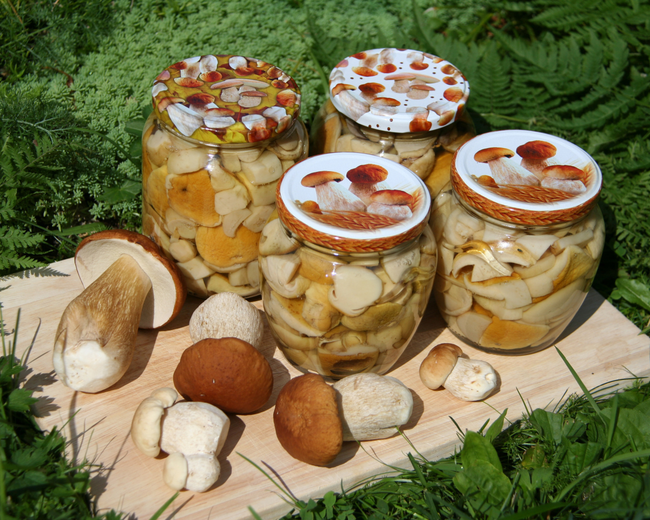Консервированные грибы в банках на разделочной доске со свежими