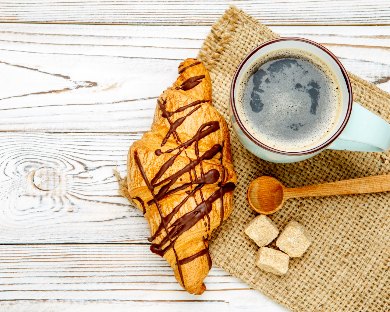 Круассан с шоколадом и чашкой кофе на столе