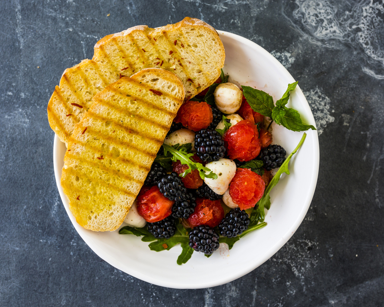 Гренки с салатом из ягод на белой тарелке