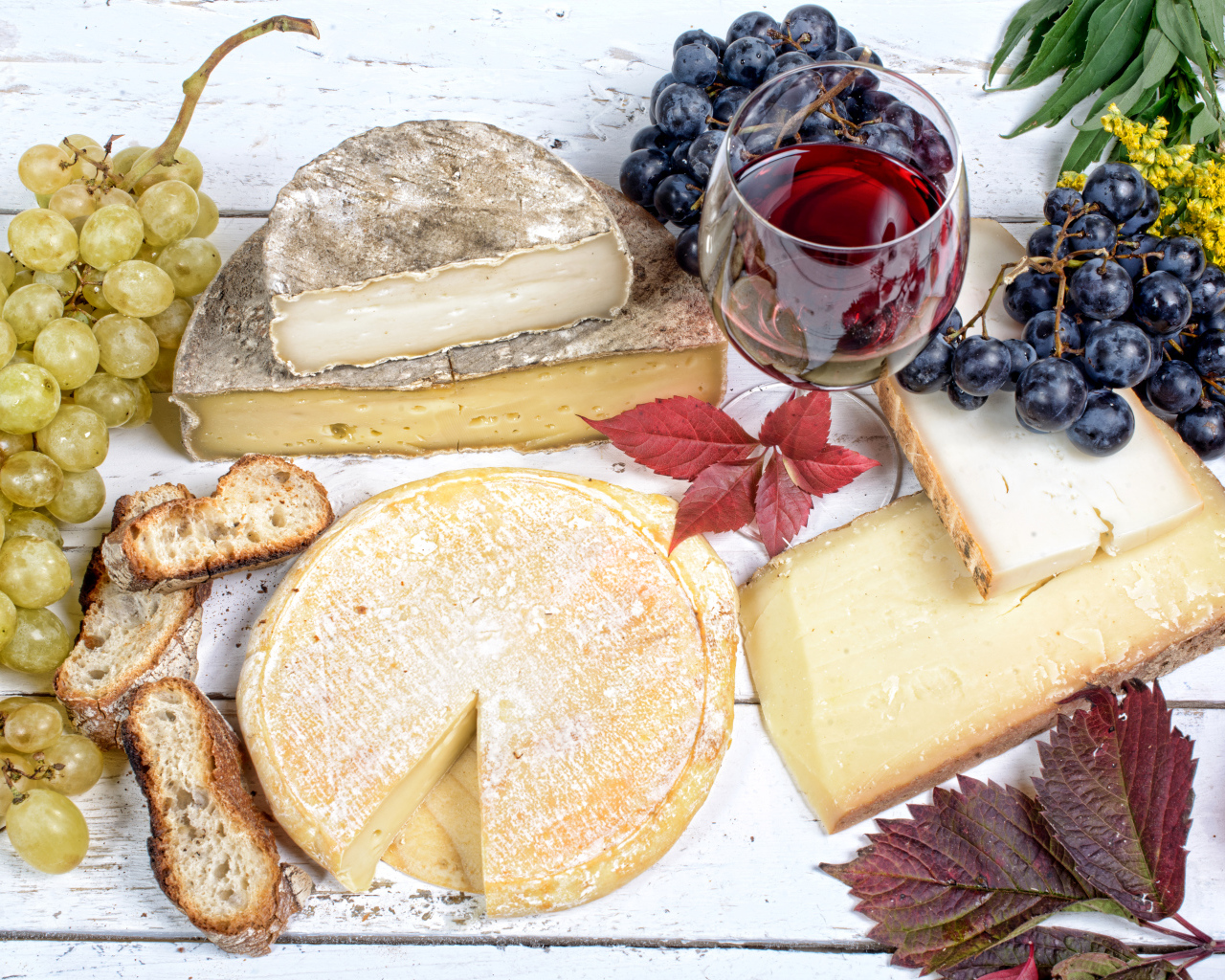 Дорогой сыр с плесенью на столе с виноградом и красным вином