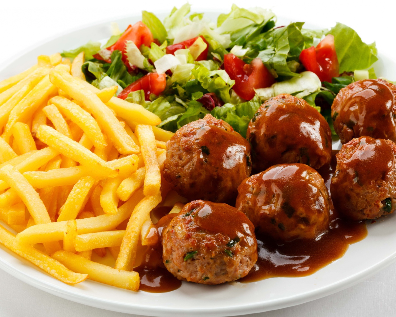 Картофель фри на белой тарелке с салатом и фрикадельками