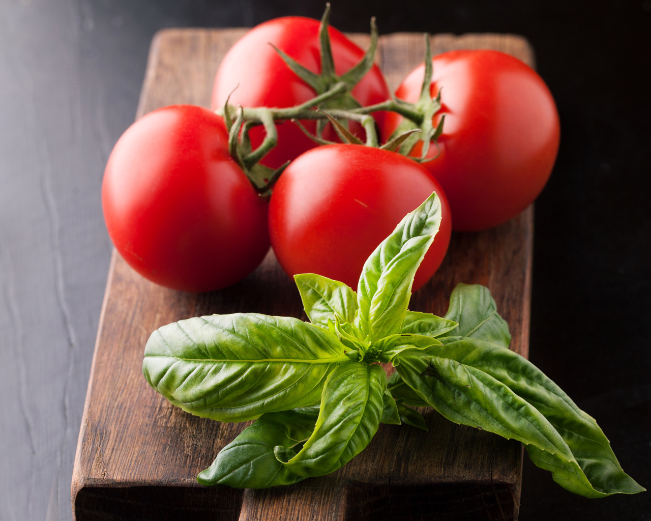 Свежие помидоры на разделочной с зеленью