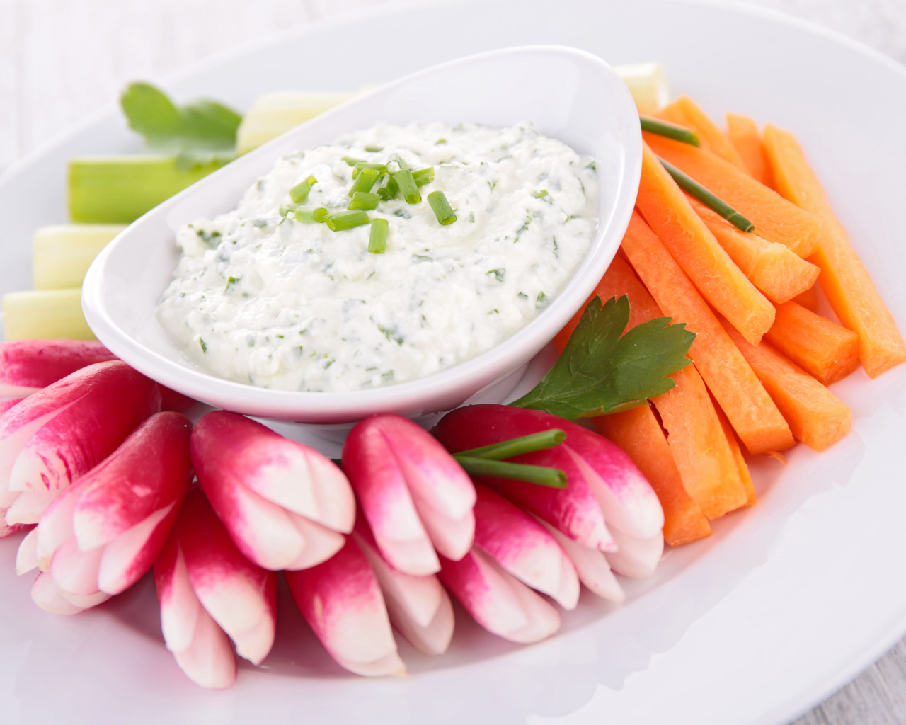 Свежие овощи с соусом в белой тарелке 