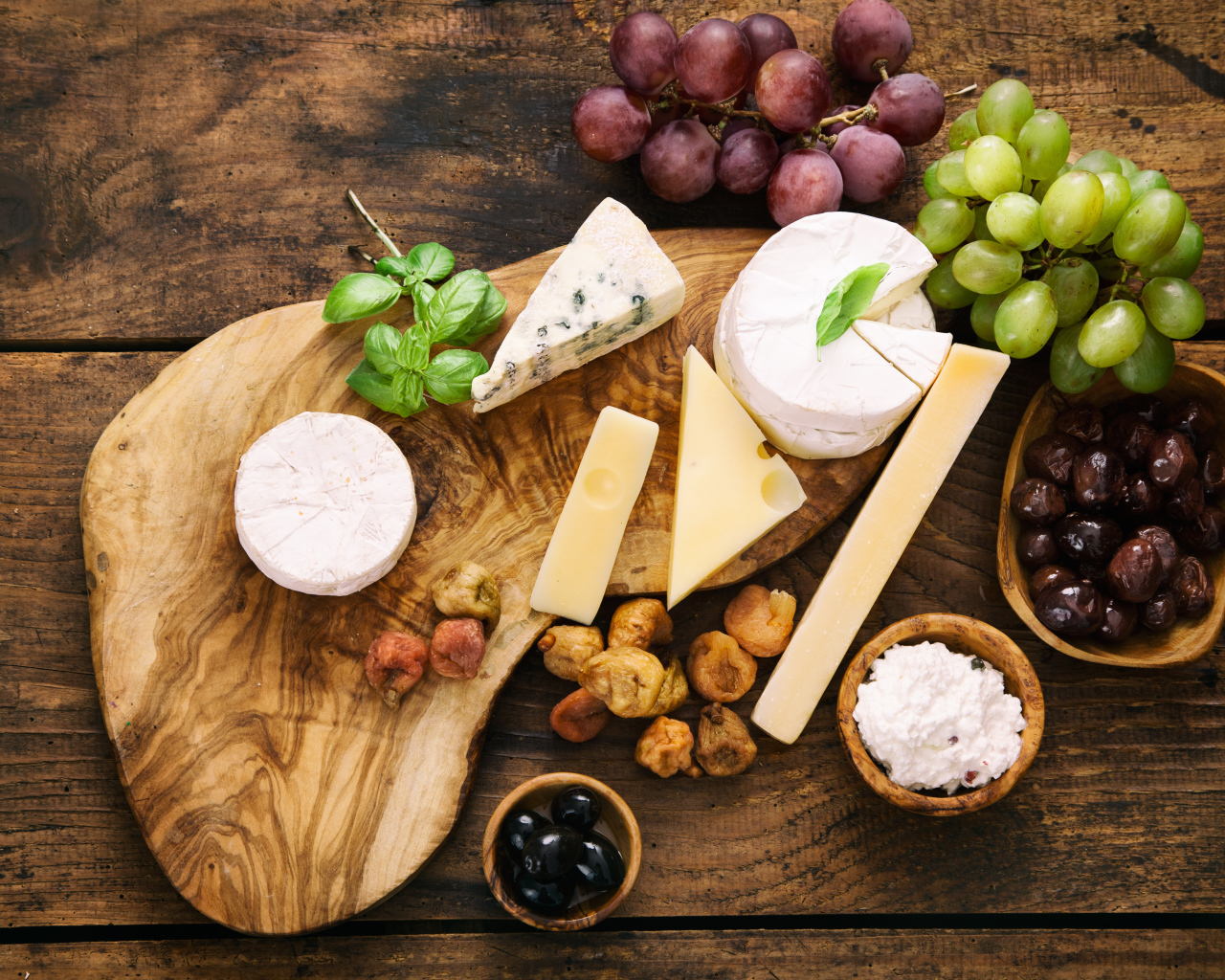 Кусочки сыра с виноградом и оливками на столе