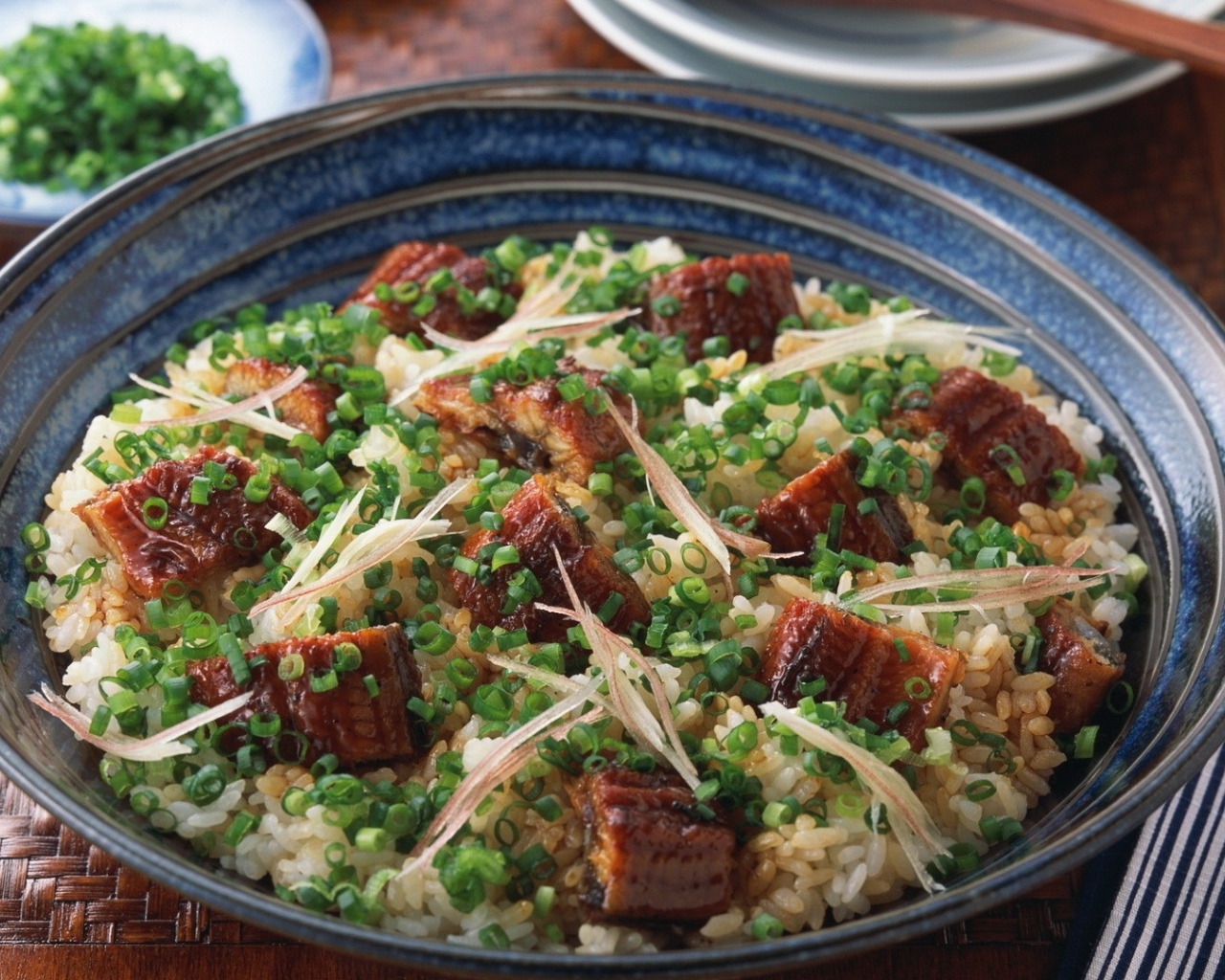 Рисовый плов с кусочками мяса и зеленым луком на столе