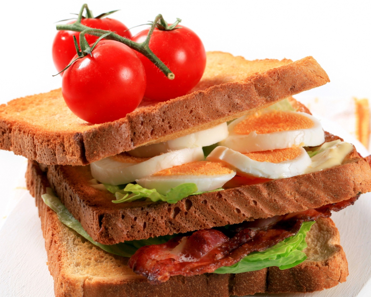 Сэндвич с беконом, яйцами и овощами на белом фоне