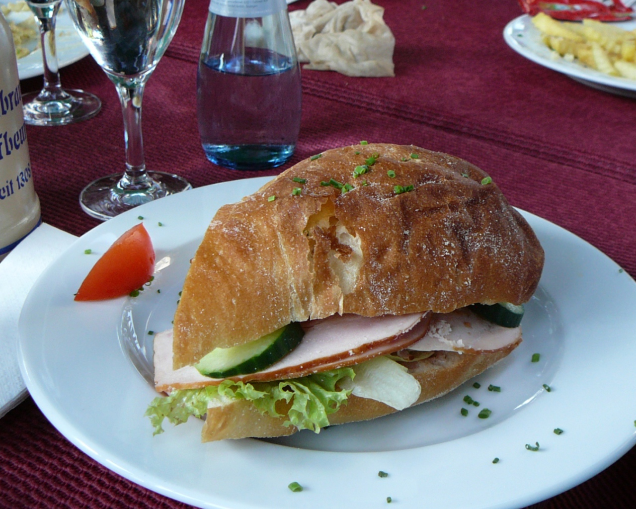 Сэндвич с ветчиной и овощами на столе в ресторане