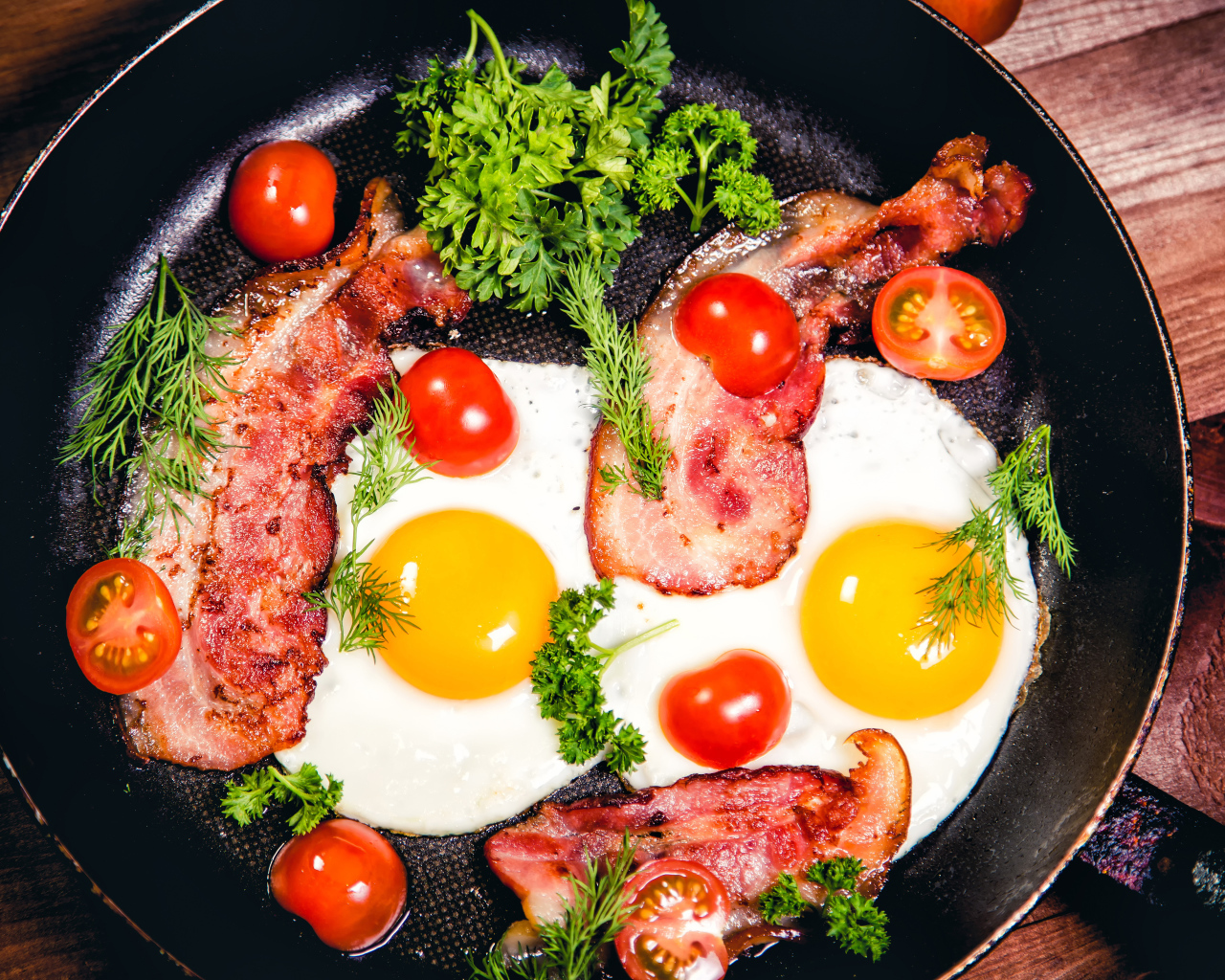 Яичница с беконом, помидорами и зеленью в сковороде на завтрак