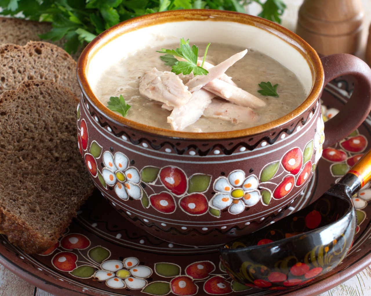 Суп с курицей в красивой тарелке на столе с черным хлебом