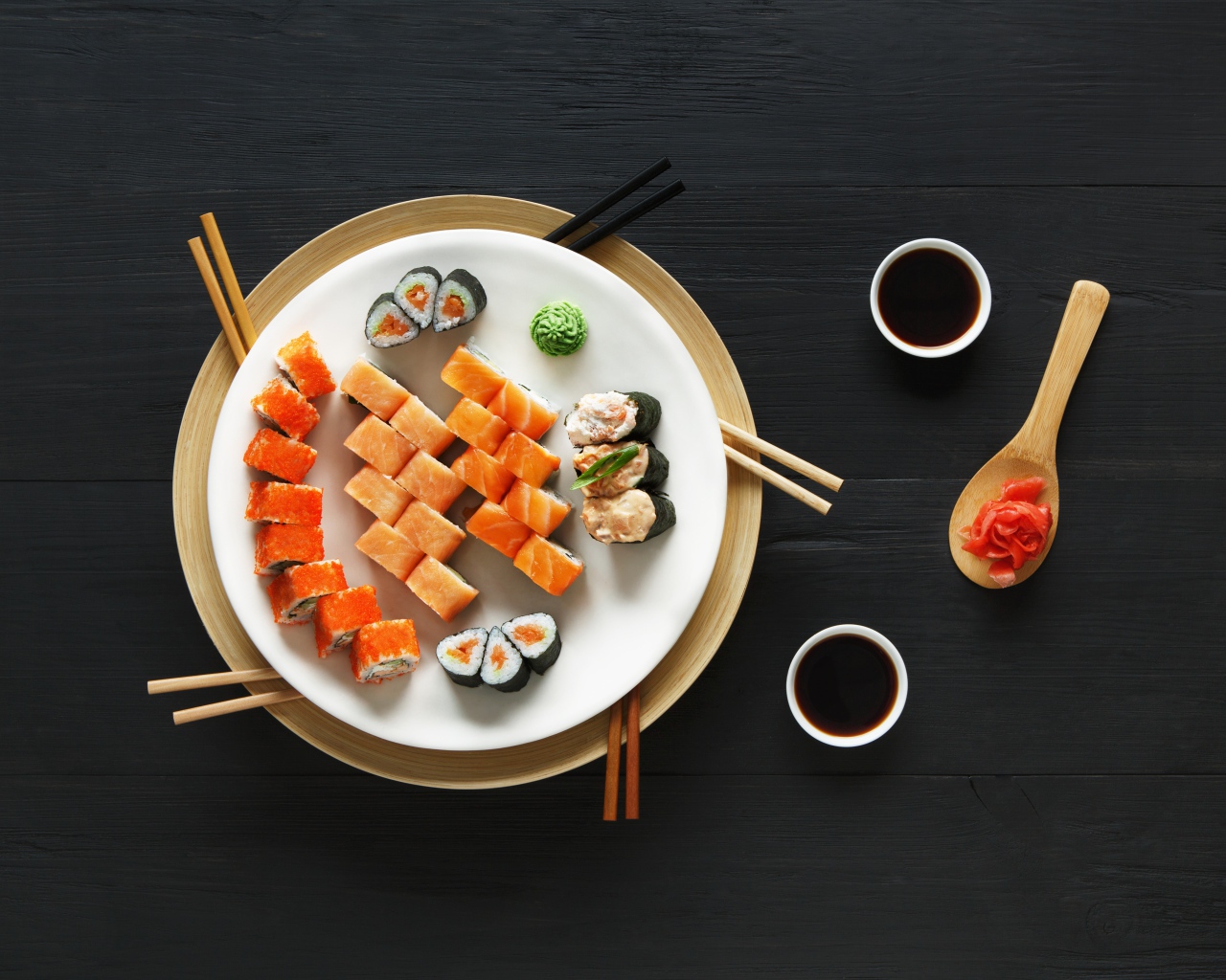 Суши и роллы на большой белой тарелке с соевым соусом