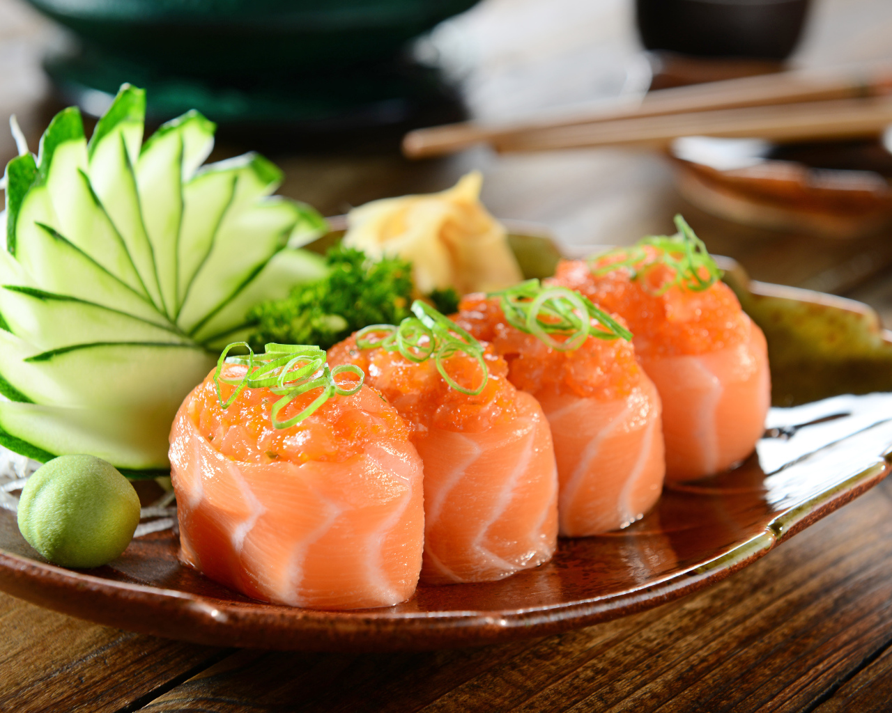 Суши из красной рыбы на тарелке со свежими огурцами и зеленью