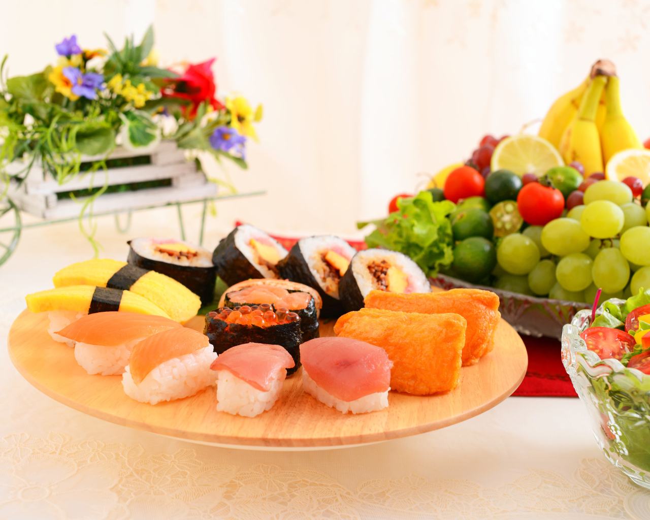 Суши на столе с фруктами и салатом из овощей