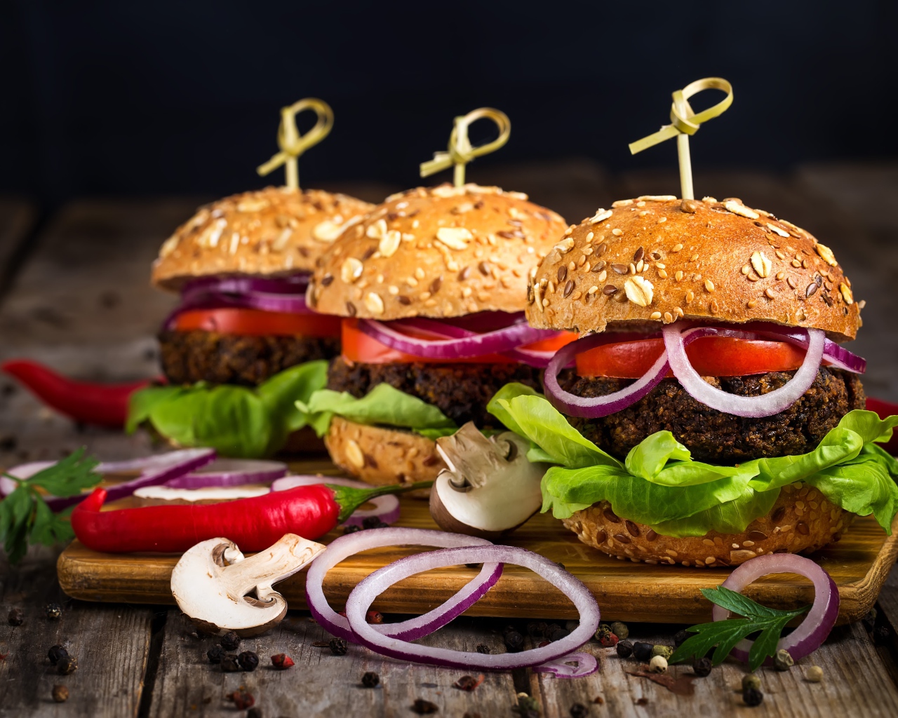 Три аппетитных гамбургера с кольцами лука и перцем