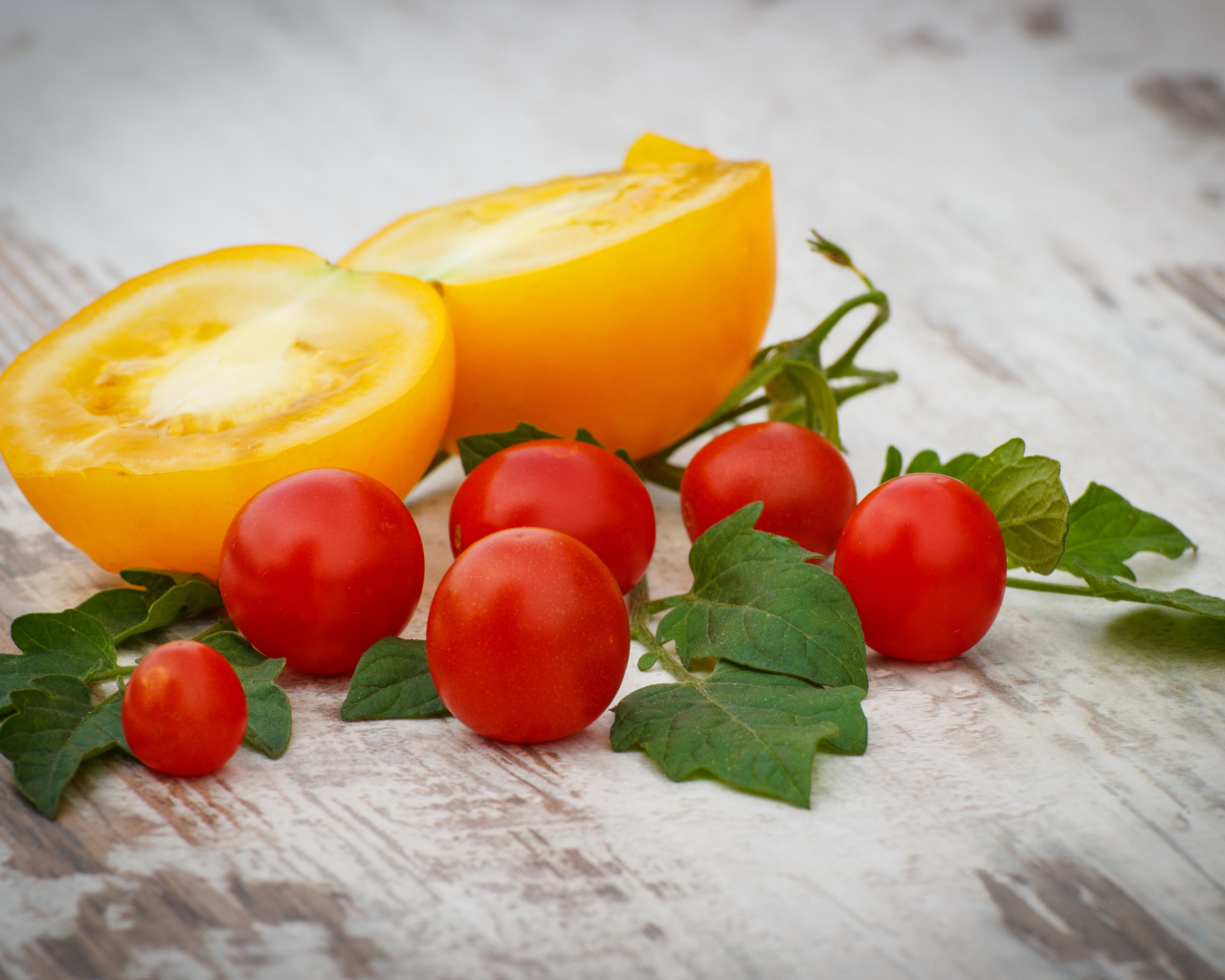 Желтые и красные помидоры на деревянной доске