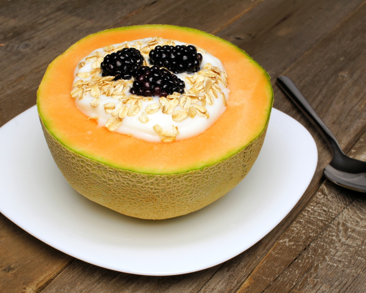 Йогурт с ежевикой и овсянкой в тарелке из свежей дыни на завтрак