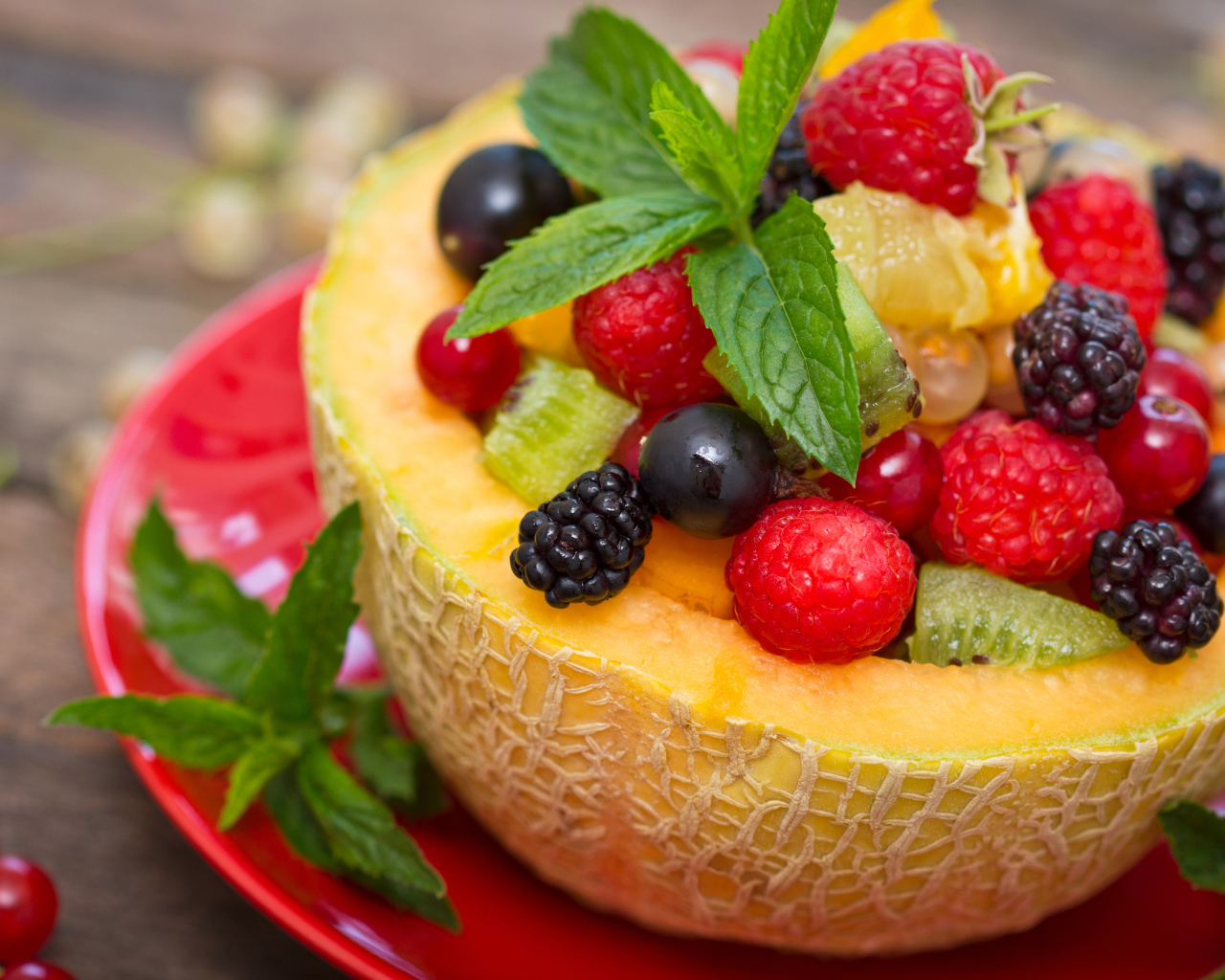 Аппетитные свежие ягоды с листьями мяты в половине дыни