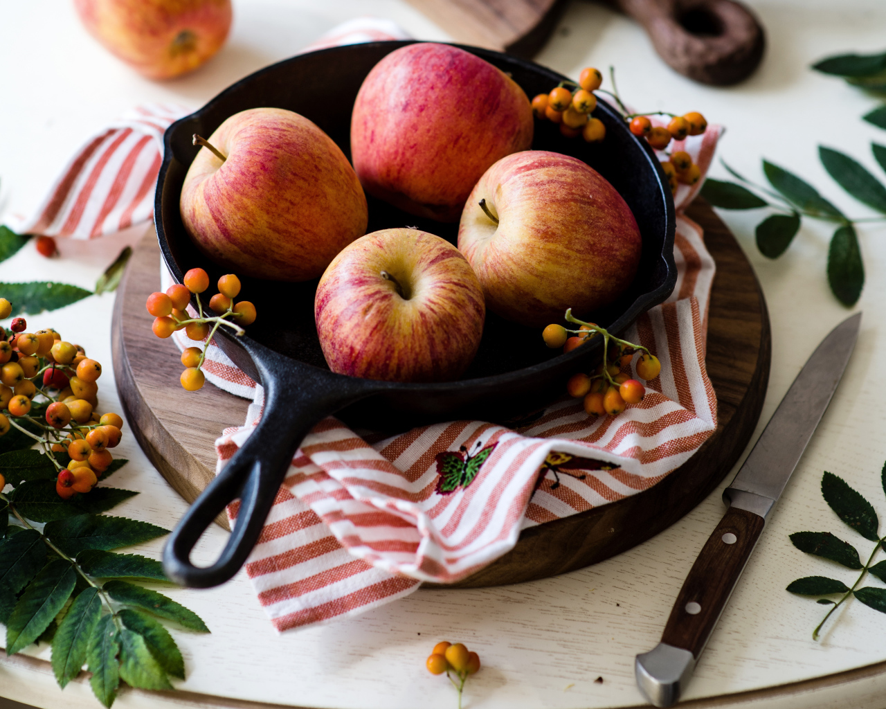 Красивые красные яблоки на сковороде с ягодами рябины