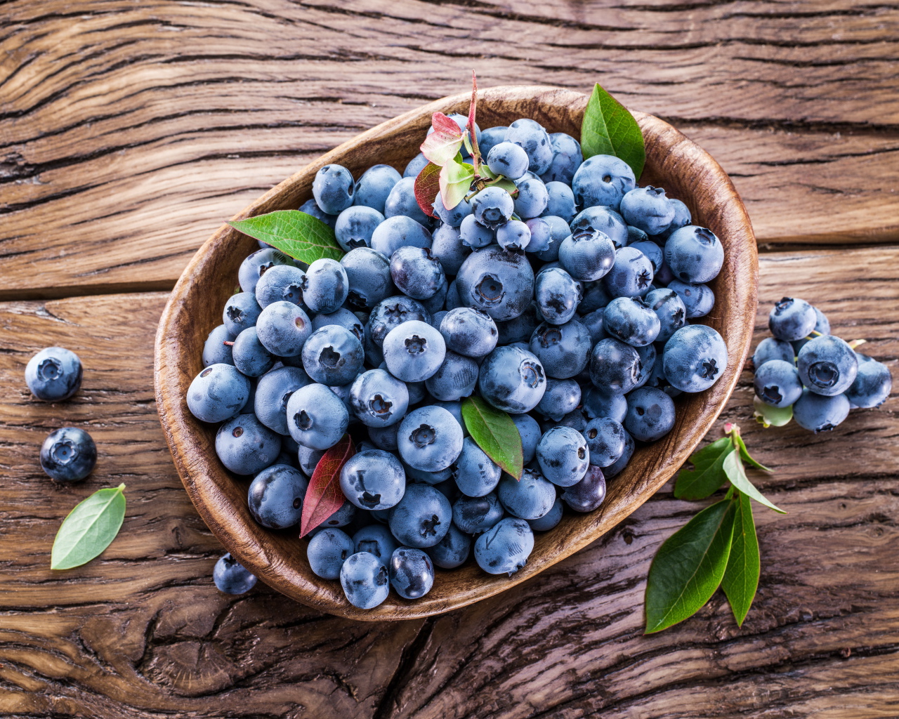 Ягоды свежей черники в тарелке на деревянном столе