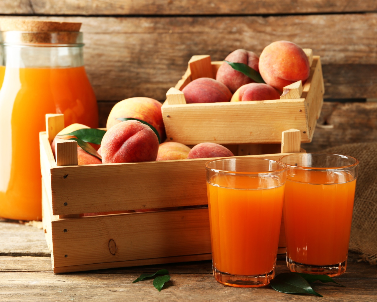 Свежие персики в деревянном ящике со свежим соком на столе