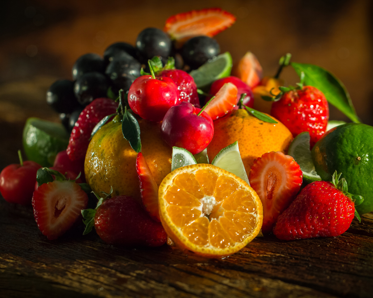 Свежие кусочки апельсина, лимона и ягоды вишни и клубники на столе