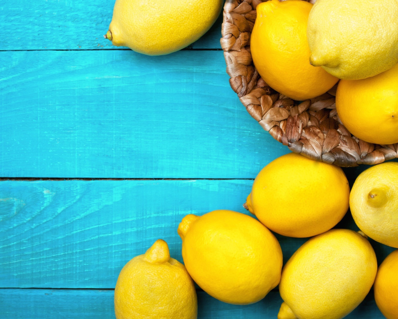 Свежие желтые лимоны лежат на голубой поверхности стола