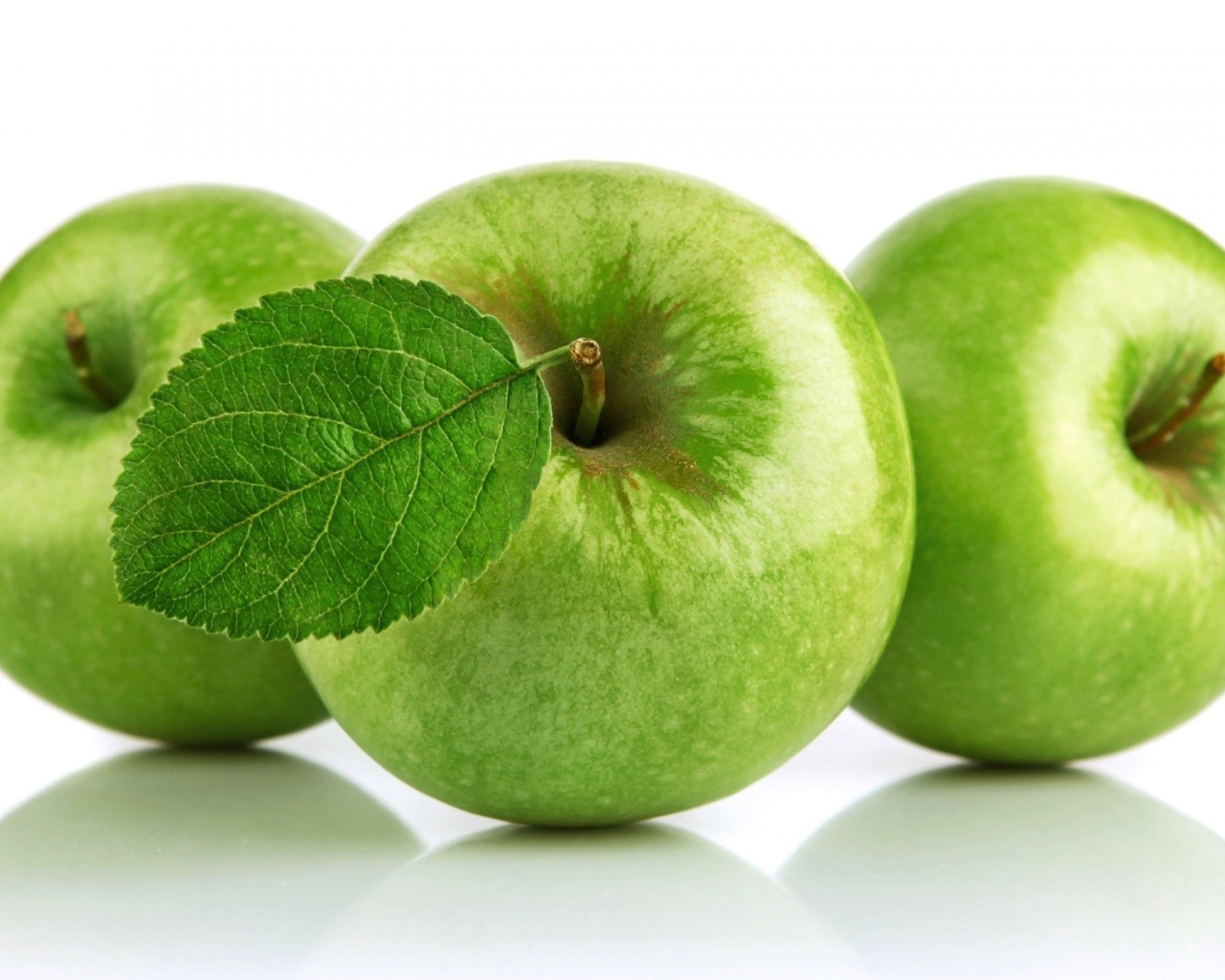 Три зеленых яблока на белом фоне 