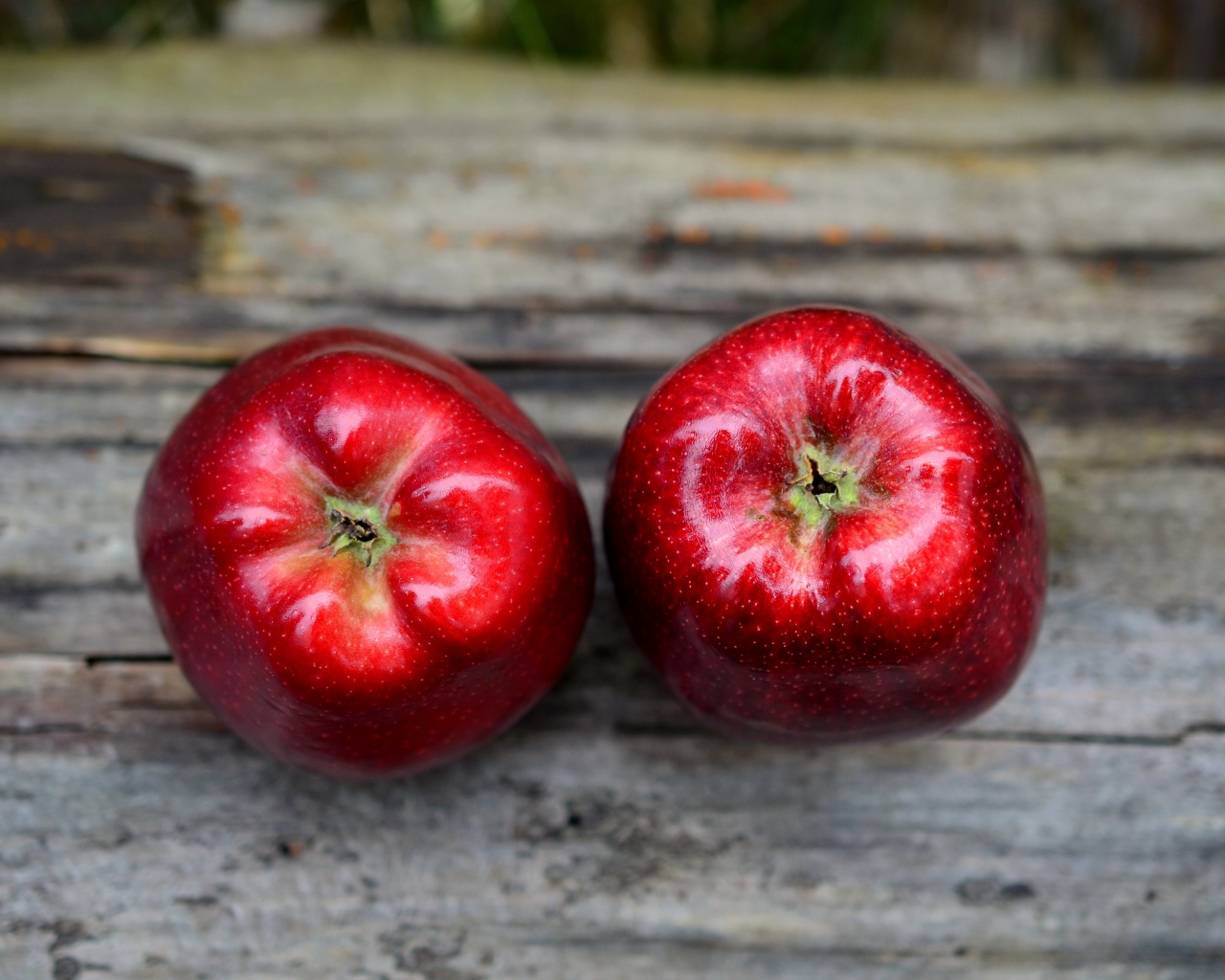 Два больших красных яблока на деревянном столе