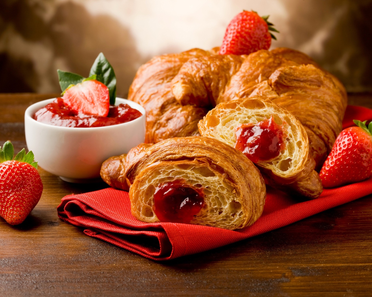 Свежие круассаны с клубничным джемом и ягодами клубники на столе