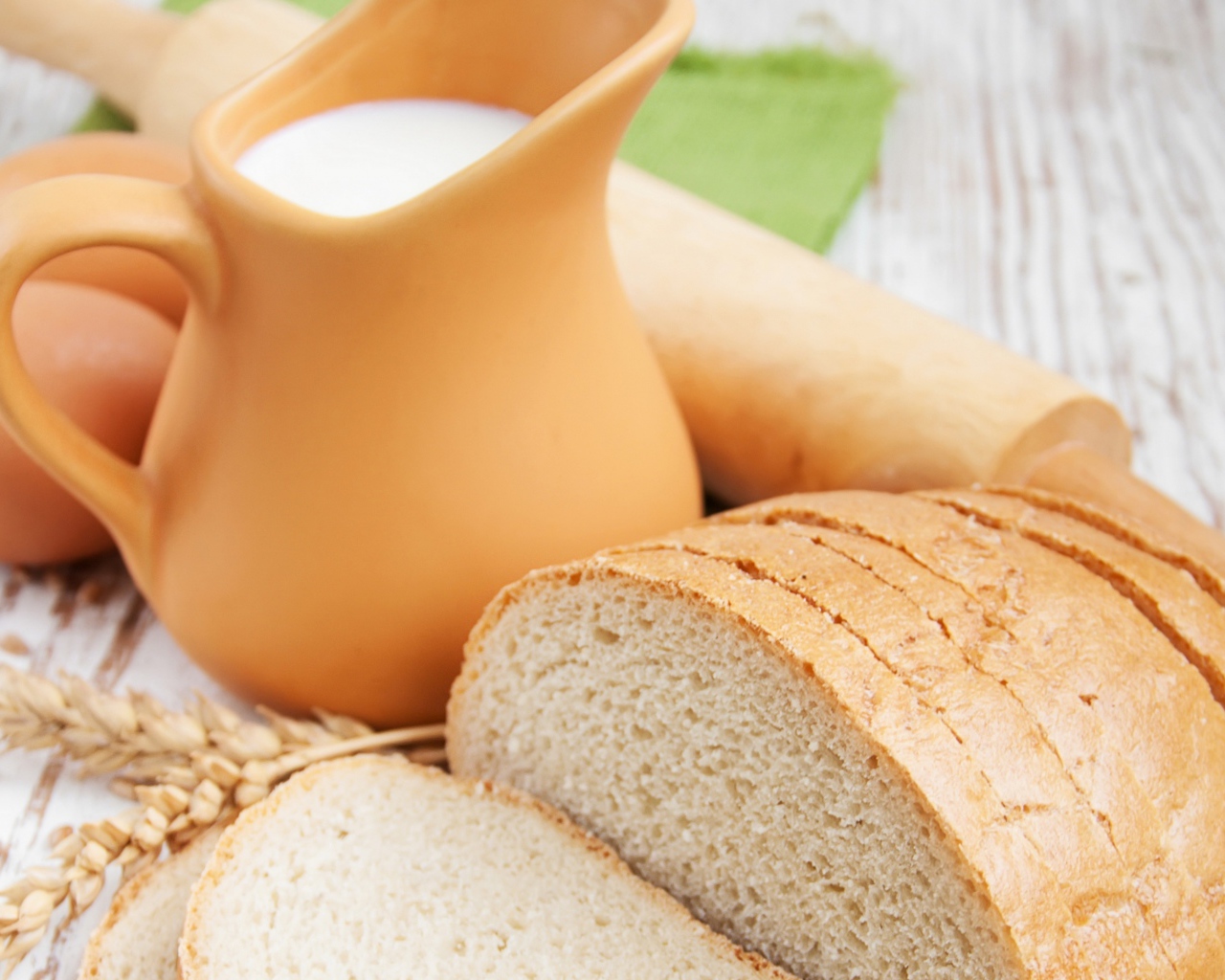 Белый нарезанный батон на столе с молоком