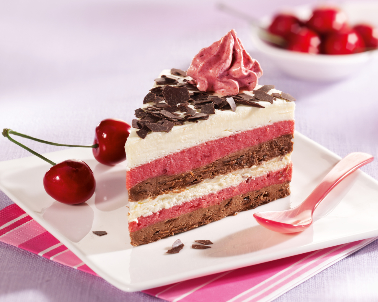 Кусок торта с вишневым и шоколадным кремом на белой тарелке