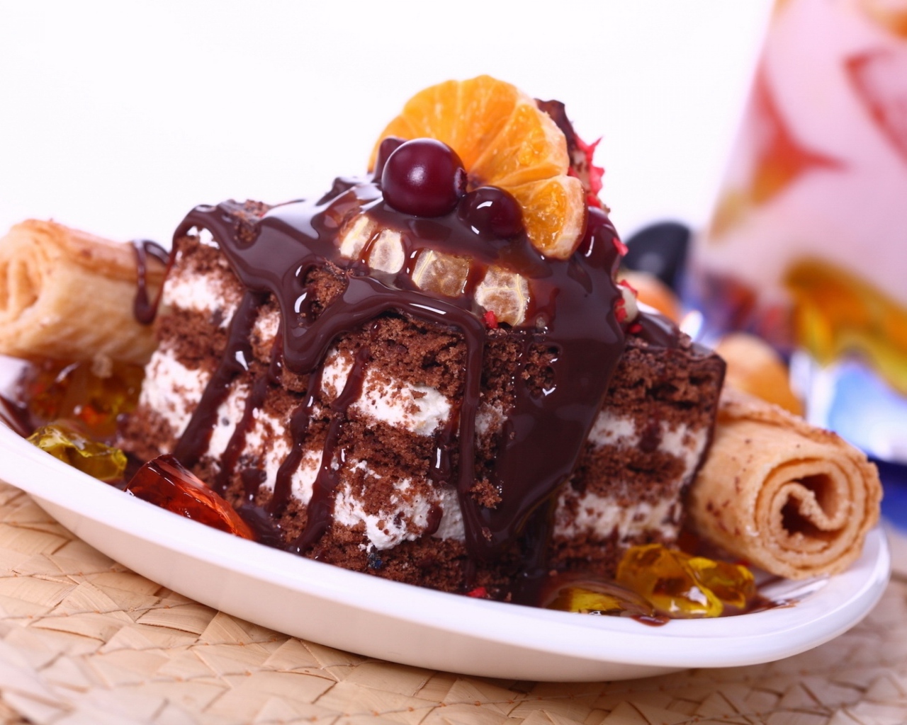 Аппетитное пирожное с шоколадной глазурью, трубочками и мандаринами