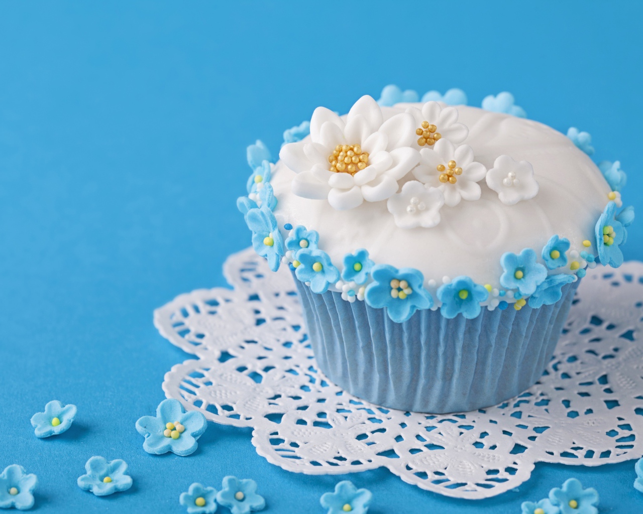 Аппетитный кекс украшен цветами на голубом фоне