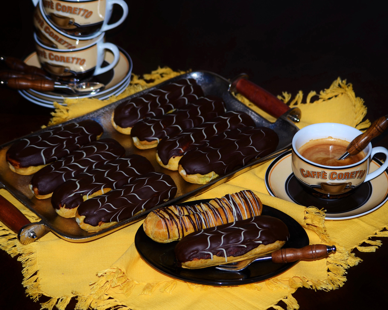 Аппетитные сладкие эклеры с шоколадом и чашками кофе на столе