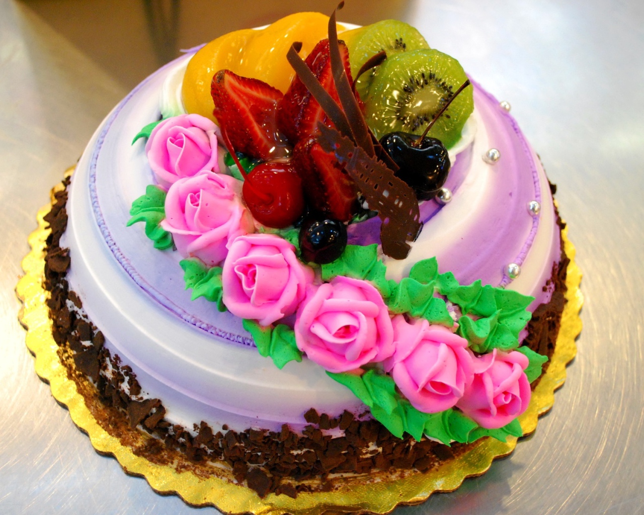 Красивый торт с фруктами украшен розовыми розами из крема