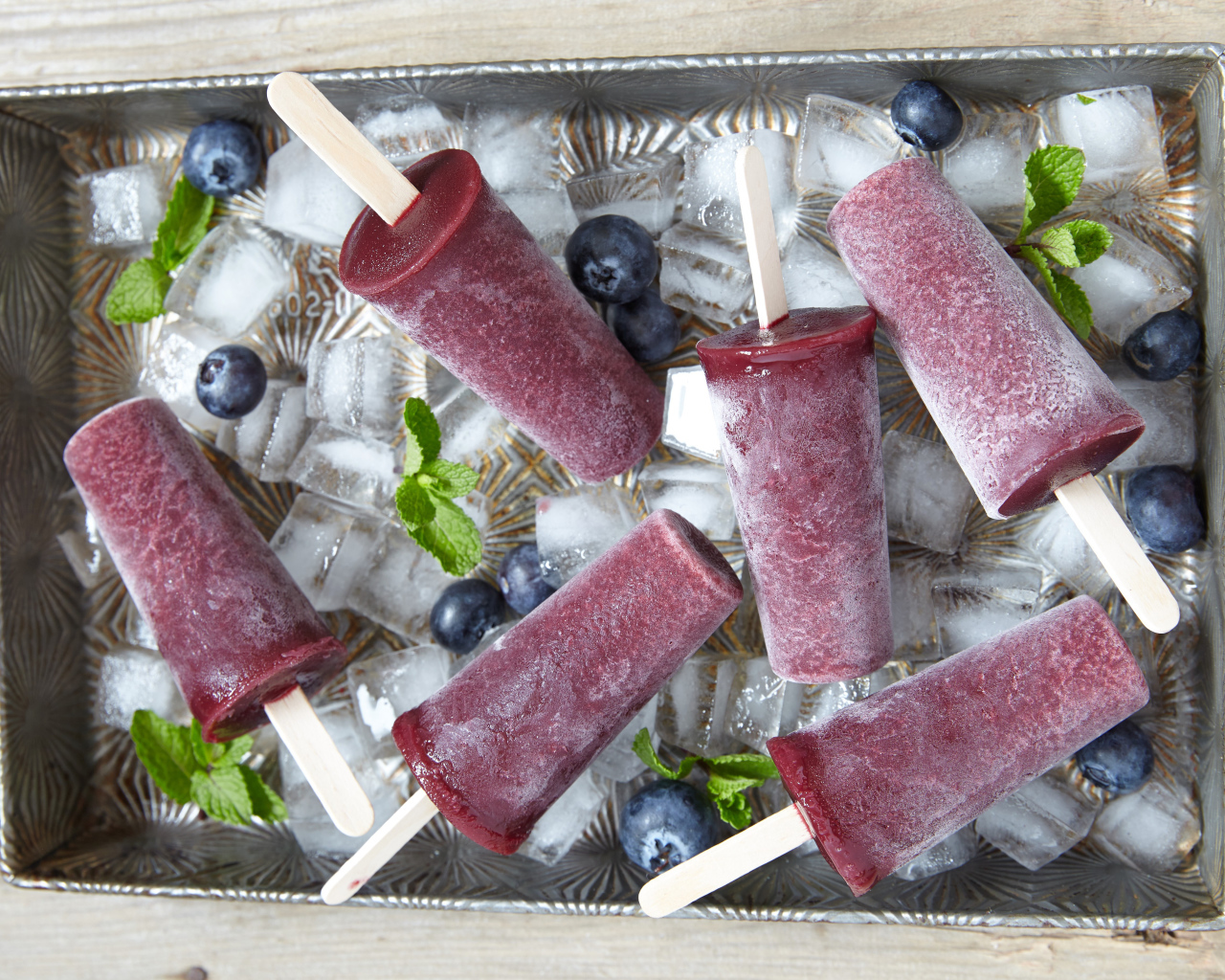 Вкусное черничное мороженое на палочке в лотке со льдом