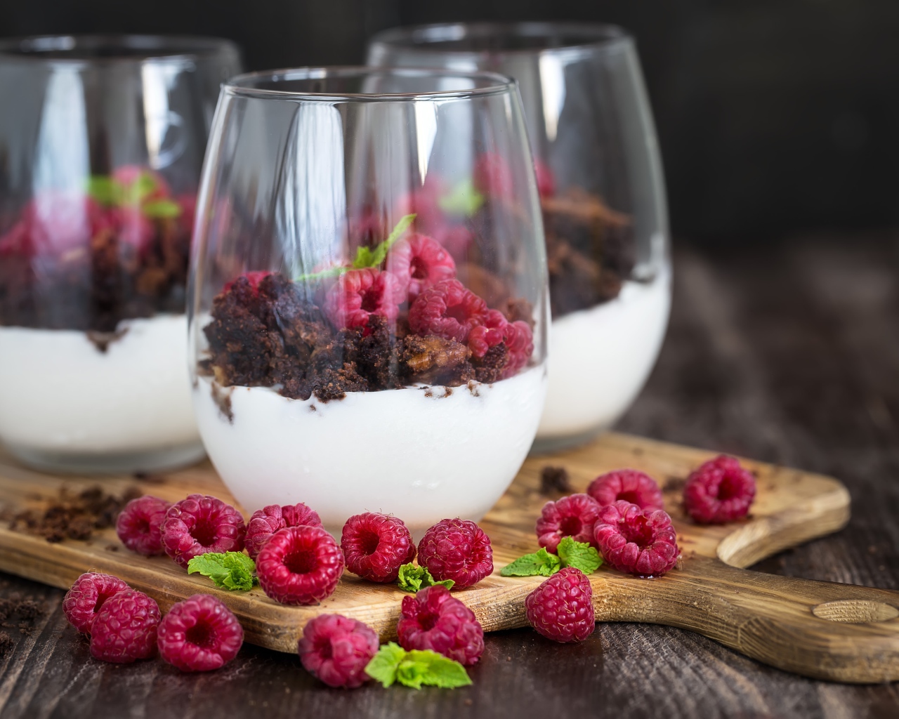 Десерт со сливками, шоколадом и свежей малиной в стеклянных стаканах