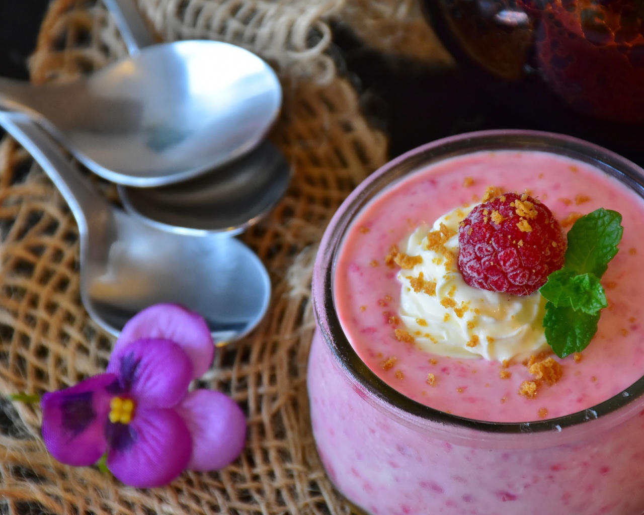 Десерт с малиной и кремом на столе с ложками