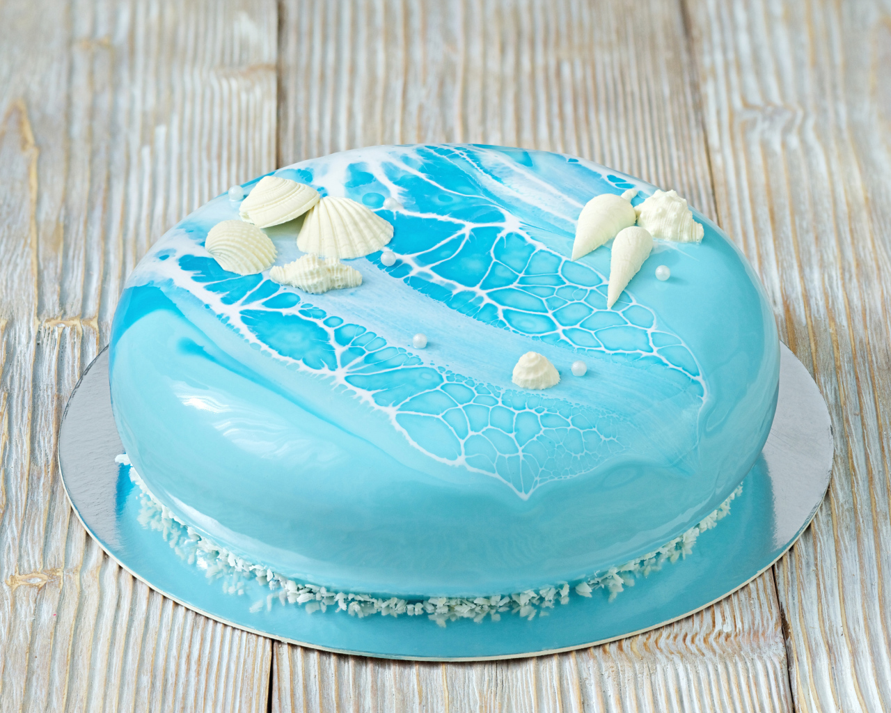 Глянцевый торт голубого цвета украшен сахарными ракушками