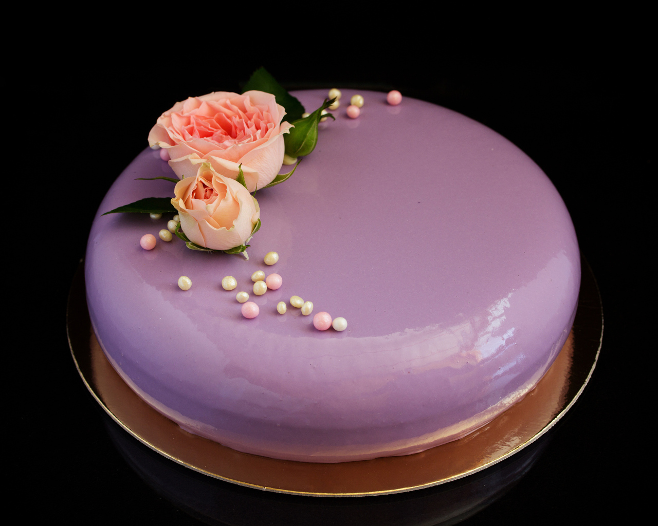 Глянцевый круглый фиолетовый торт с цветами розы на черном фоне