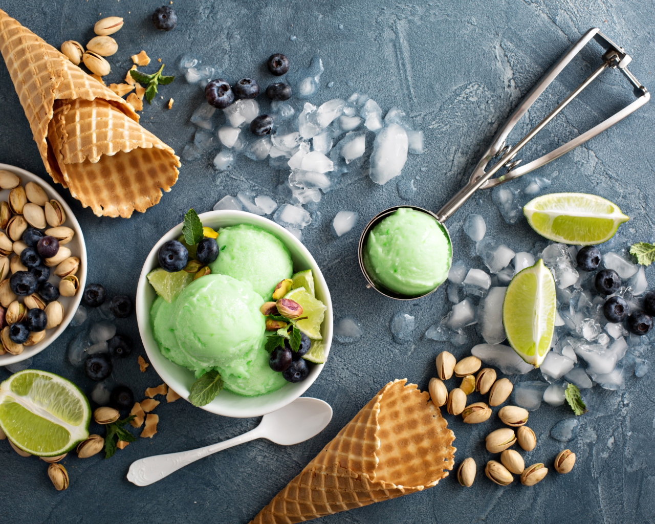 Мороженое с лаймом и фисташками на столе с вафельными рожками и льдом