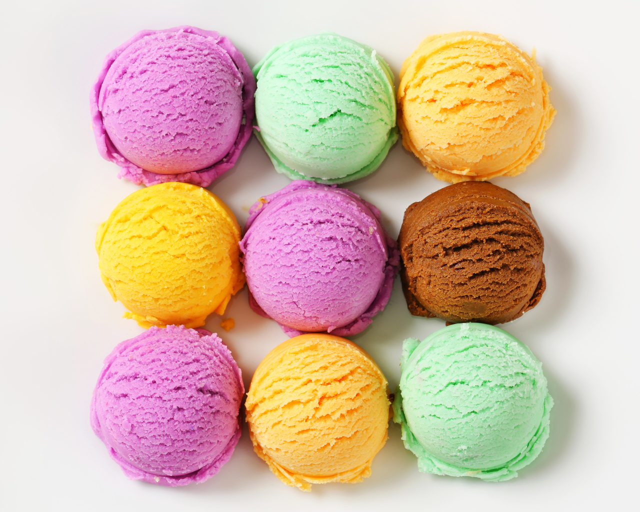 Разноцветные аппетитные шарики мороженого на белом фоне