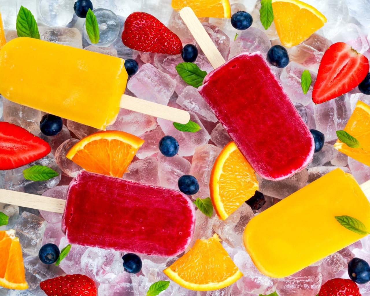 Разноцветное фруктовое мороженое с ягодами лежит на кусочках льда