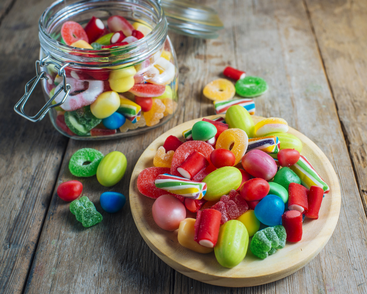 Разноцветные мармеладные конфеты в стеклянной банке на столе